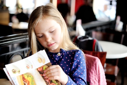 Little girl looking at a menu in cafe